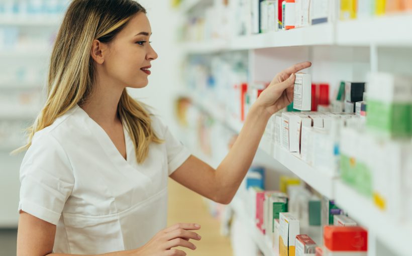 Młoda farmaceutka układa leki na półce w aptece. /Źródło: 123rf.com