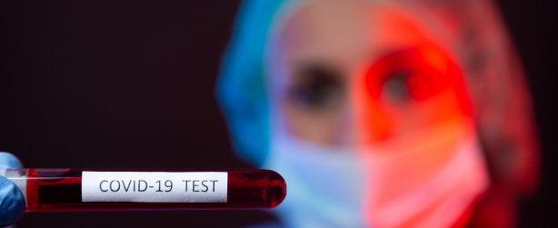 Pielęgniarka w sterylnym stroju trzyma w dłoniach fiolkę z próbką krwi. /Źródło: 123rf.com