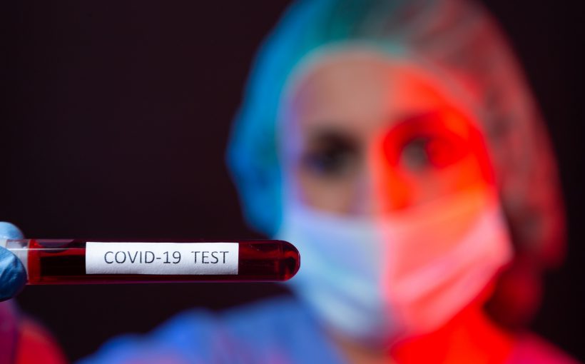 Pielęgniarka w sterylnym stroju trzyma w dłoniach fiolkę z próbką krwi. /Źródło: 123rf.com