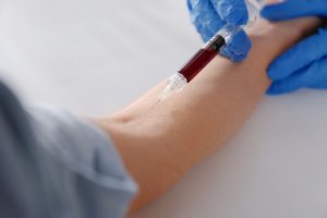 Pacjentowi pobierana jest krew z żyły ręki przez doświadczonego pielęgniarza.