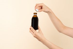 Kobieta trzyma w dłoni buteleczkę z syropem. /Źródło: 123rf.com