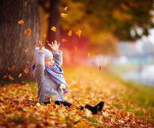 Mała dziewczynka bawi się liśćmi w parku w czasie jesieni. /Źródło: 123rf.com