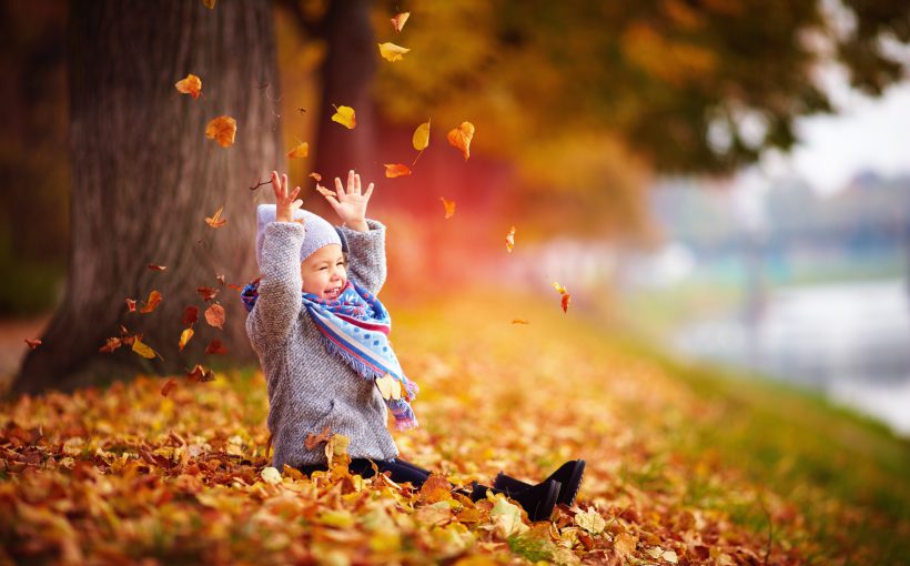 Mała dziewczynka bawi się liśćmi w parku w czasie jesieni. /Źródło: 123rf.com