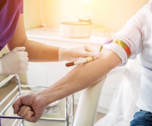Nurse taking a patient's blood sample at lab.
