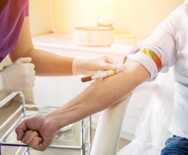 Nurse taking a patient's blood sample at lab.
