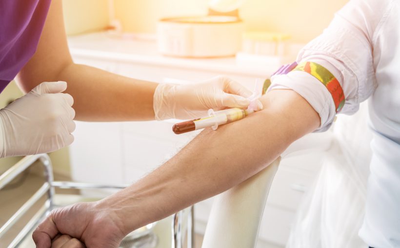 Nurse taking a patient's blood sample at lab.