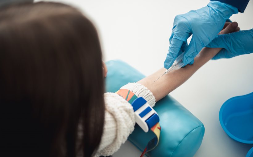 Professional laboratory investigations in healthcare system. Back side top view portrait of female child in process of having haemanalysis in medical office