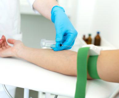 a nurse in the clinic inserts a catheter into a vein for blood testing for a young girl.