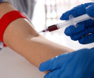 Nurse drawing blood sample from patient in clinic, closeup