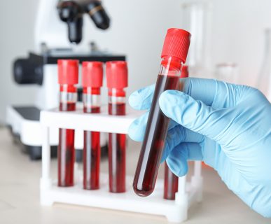 Scientist taking test tube with blood sample from rack at table, closeup. Laboratory analysis